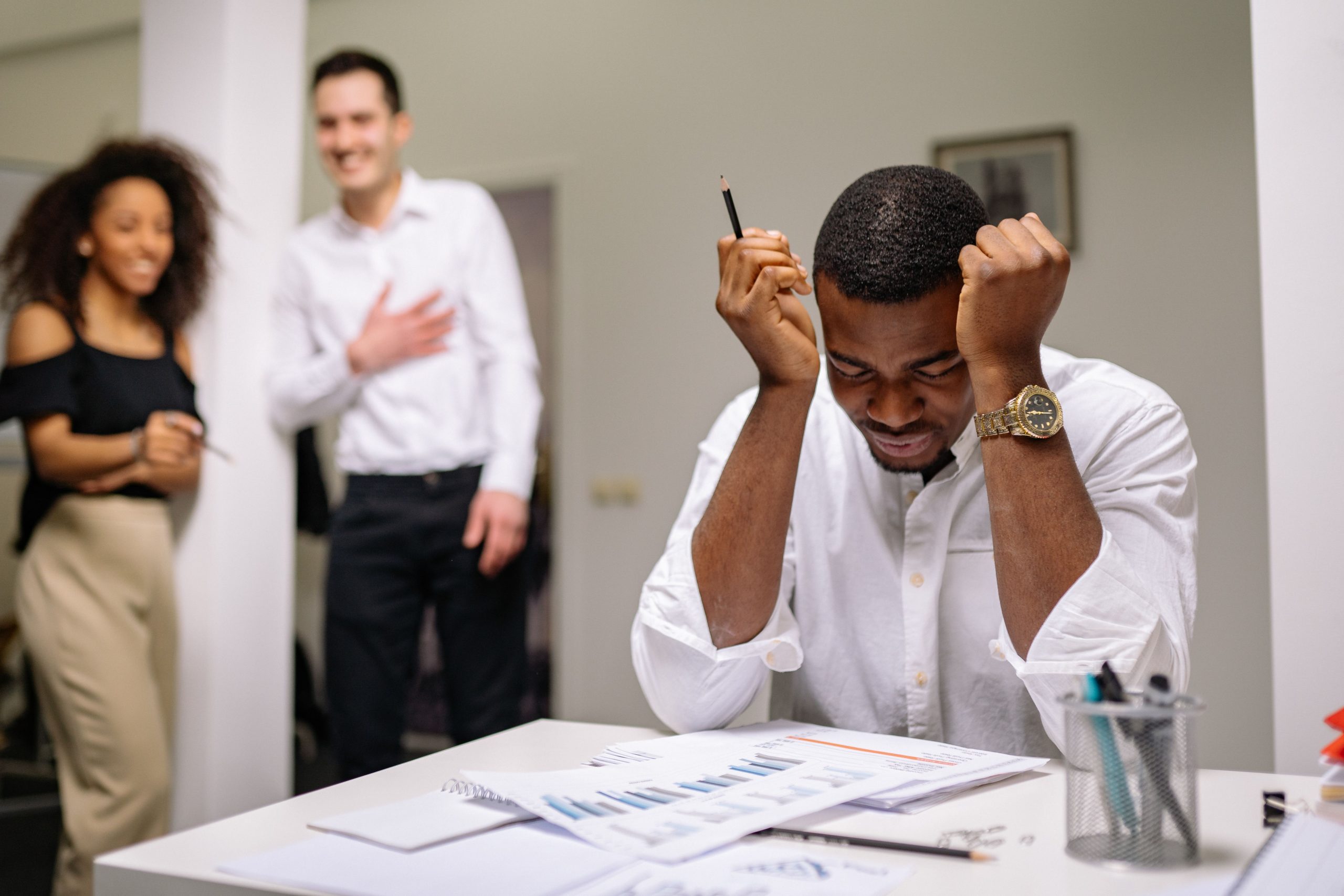 Homme stressé entouré de collègues au travail
