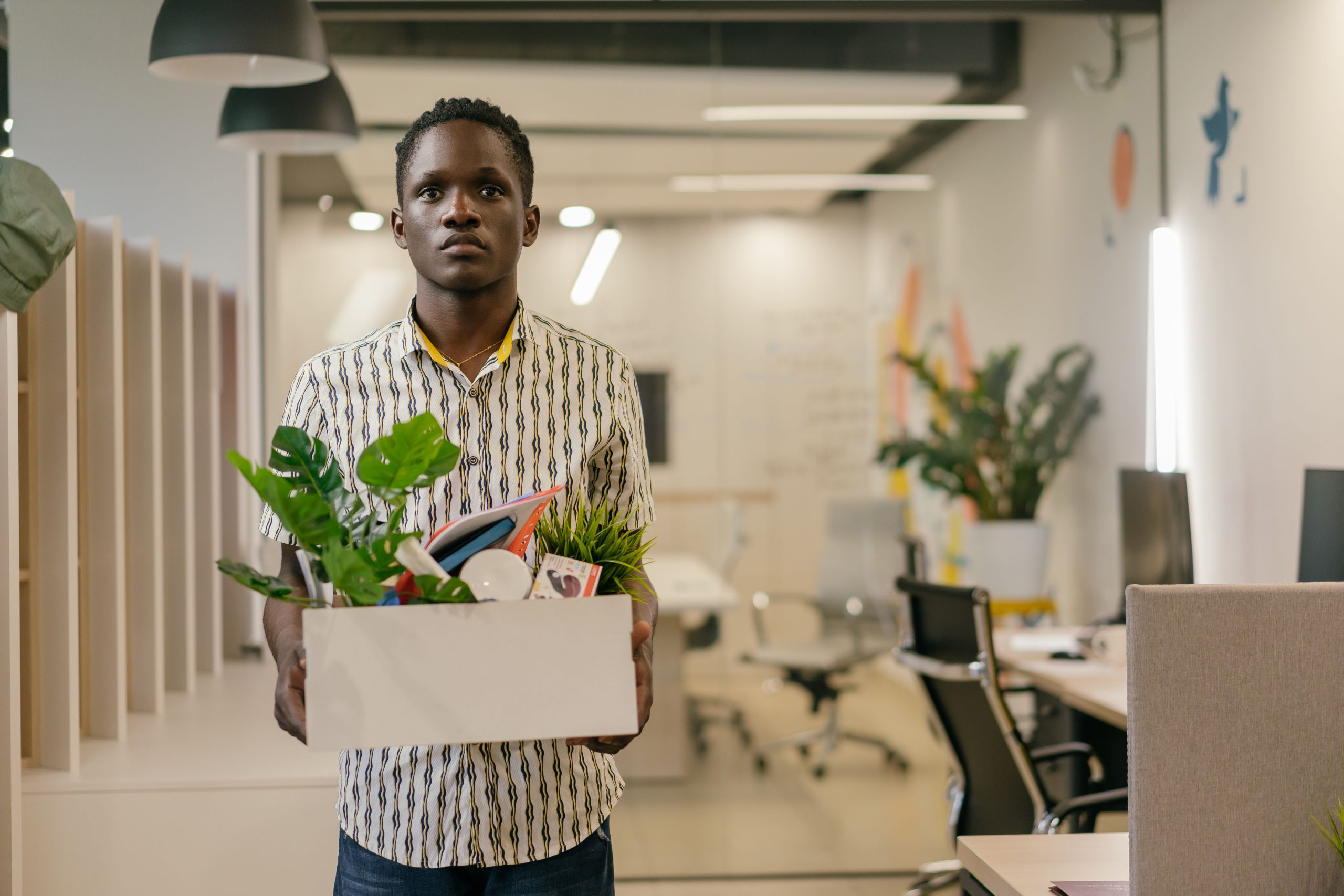 Homme portant boîte affaires quittant bureau