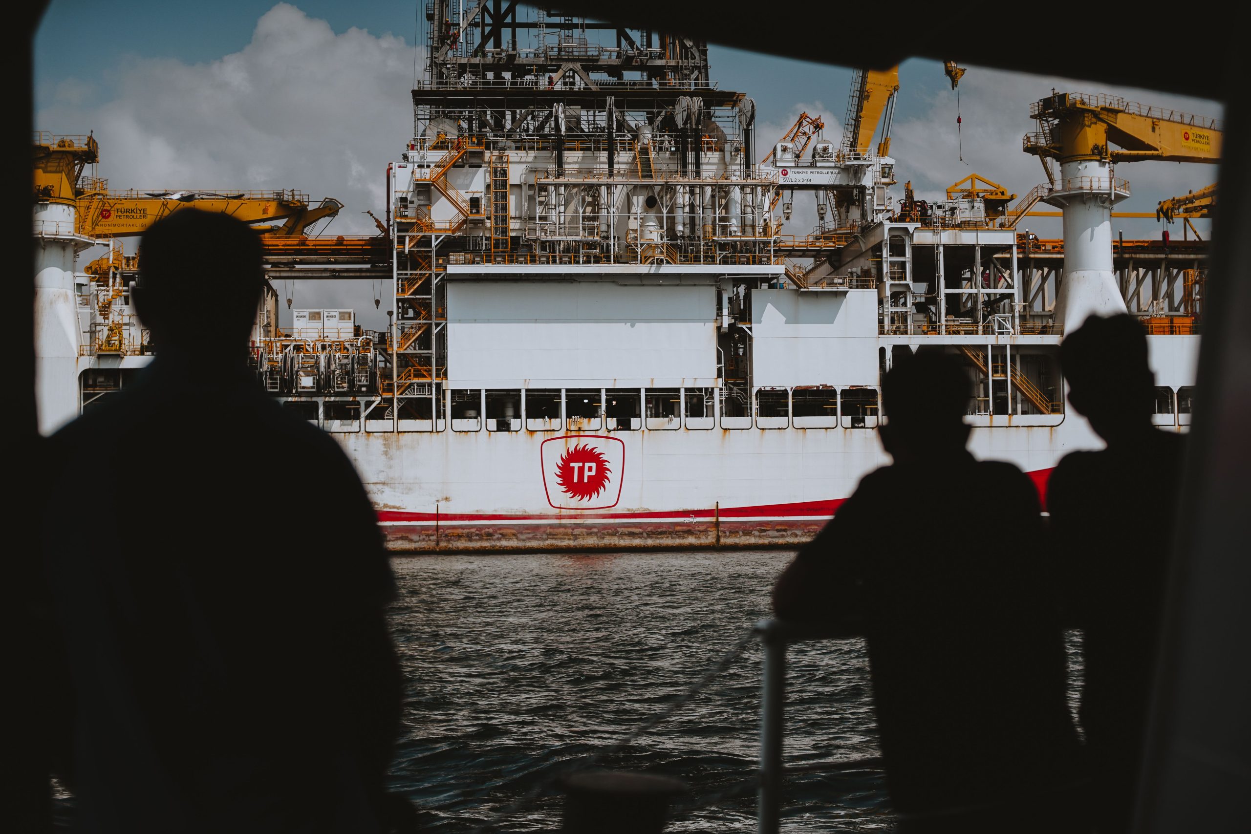 Silhouettes observant une plateforme pétrolière offshore