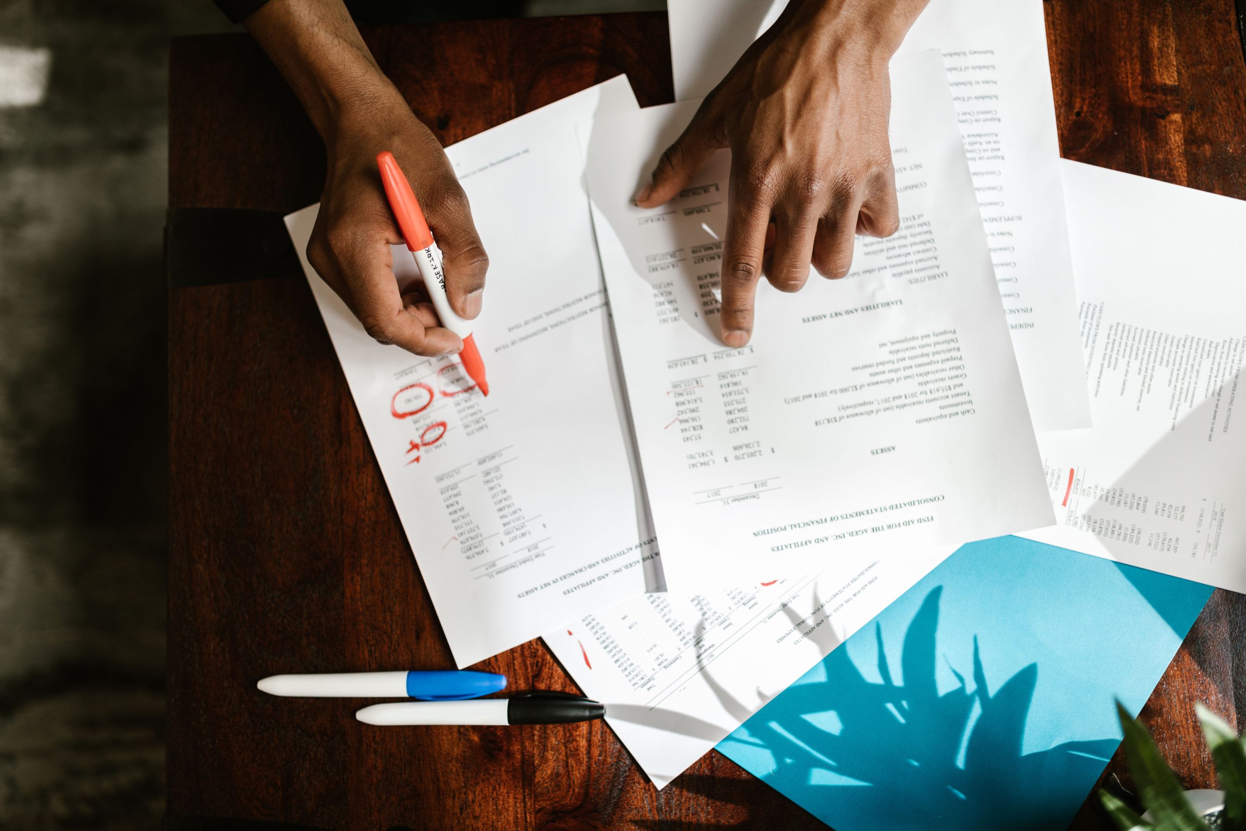 Vue de dessus mains surlignant documents financiers