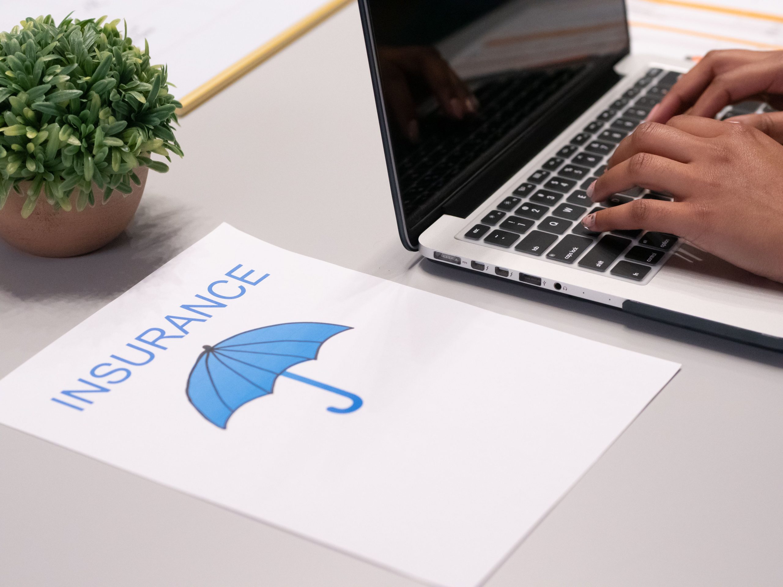 Mains tapant sur ordinateur avec document assurance visible