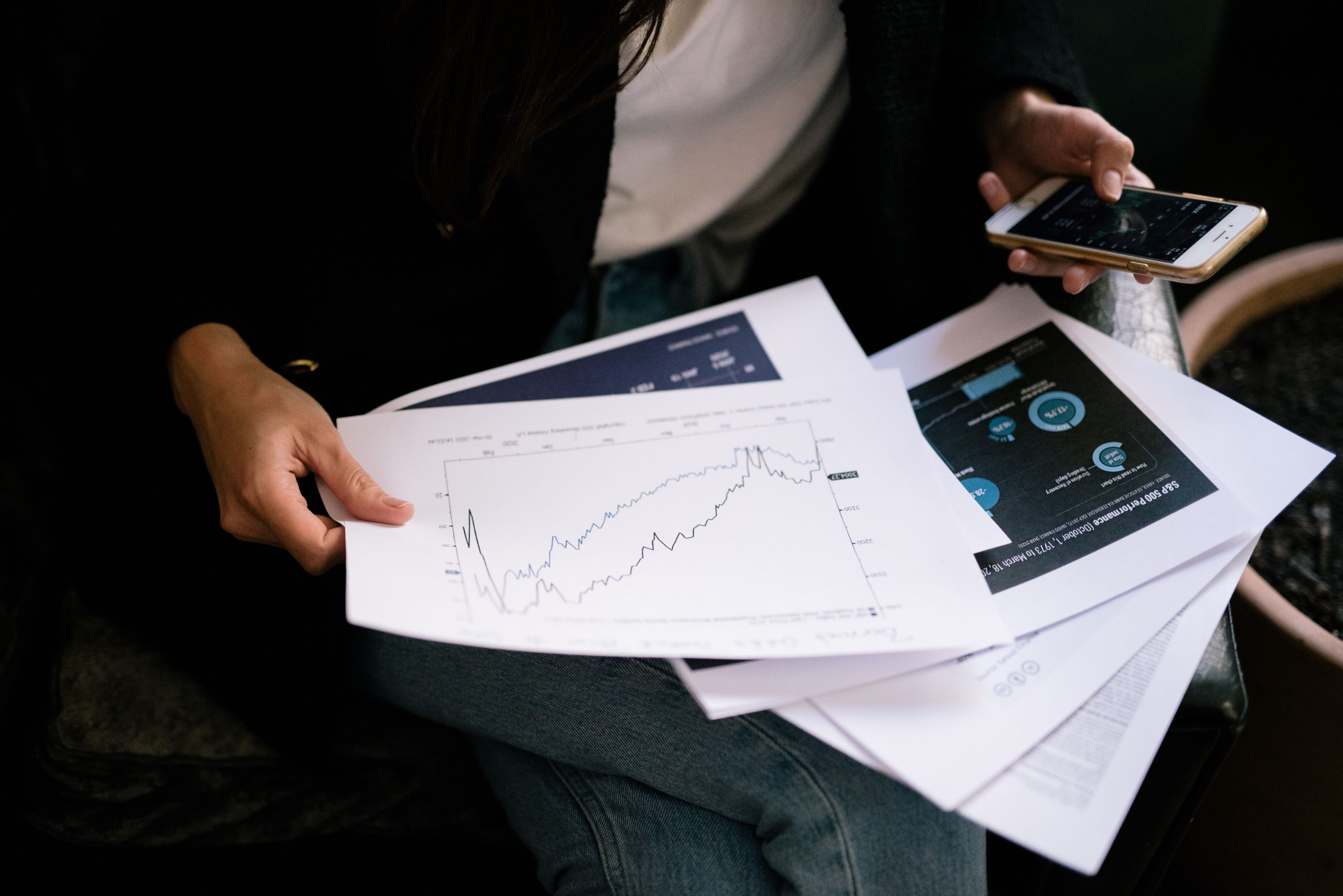 Personne examinant graphiques bourse sur papier smartphone