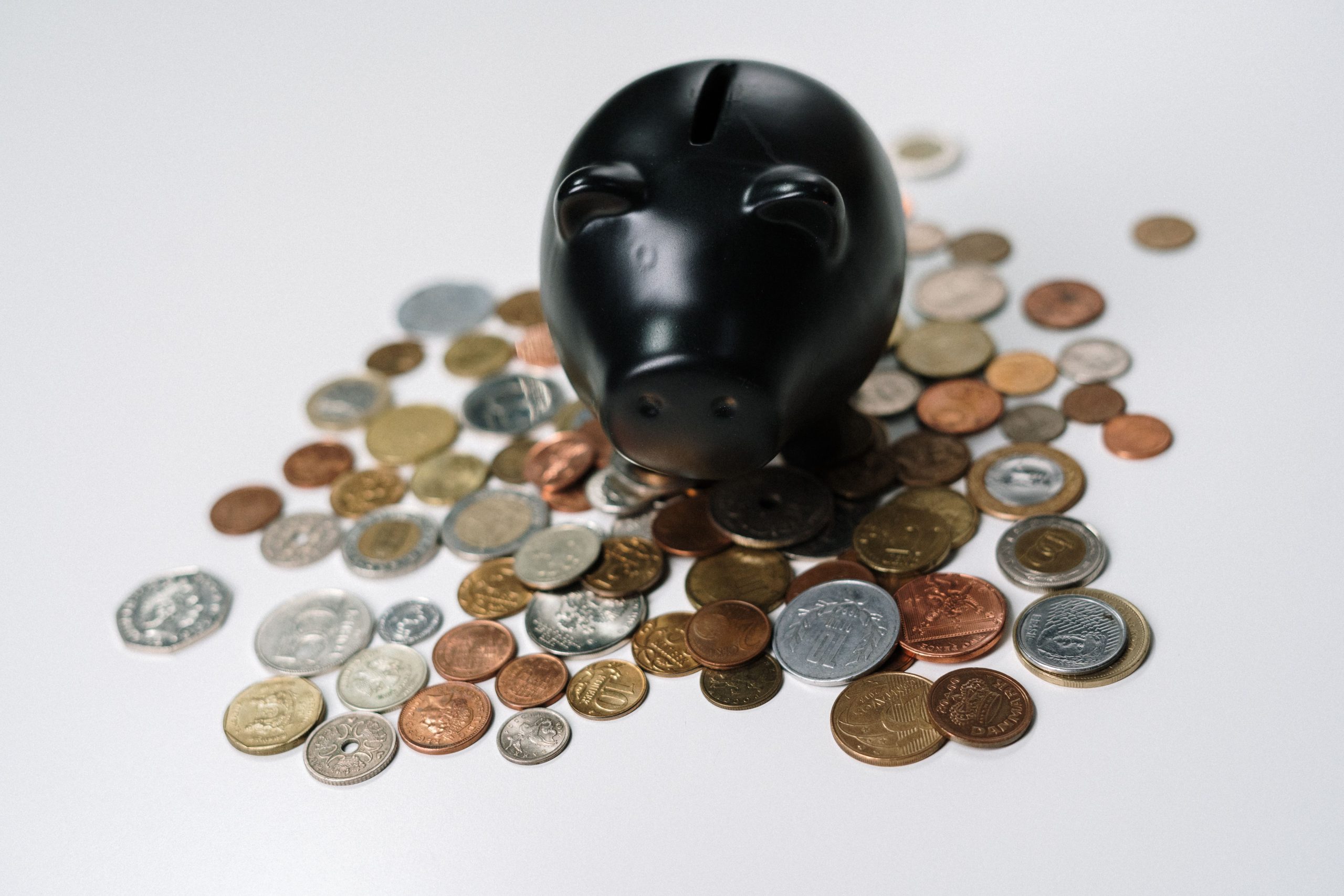Tirelire noire entourée de pièces de monnaie variées