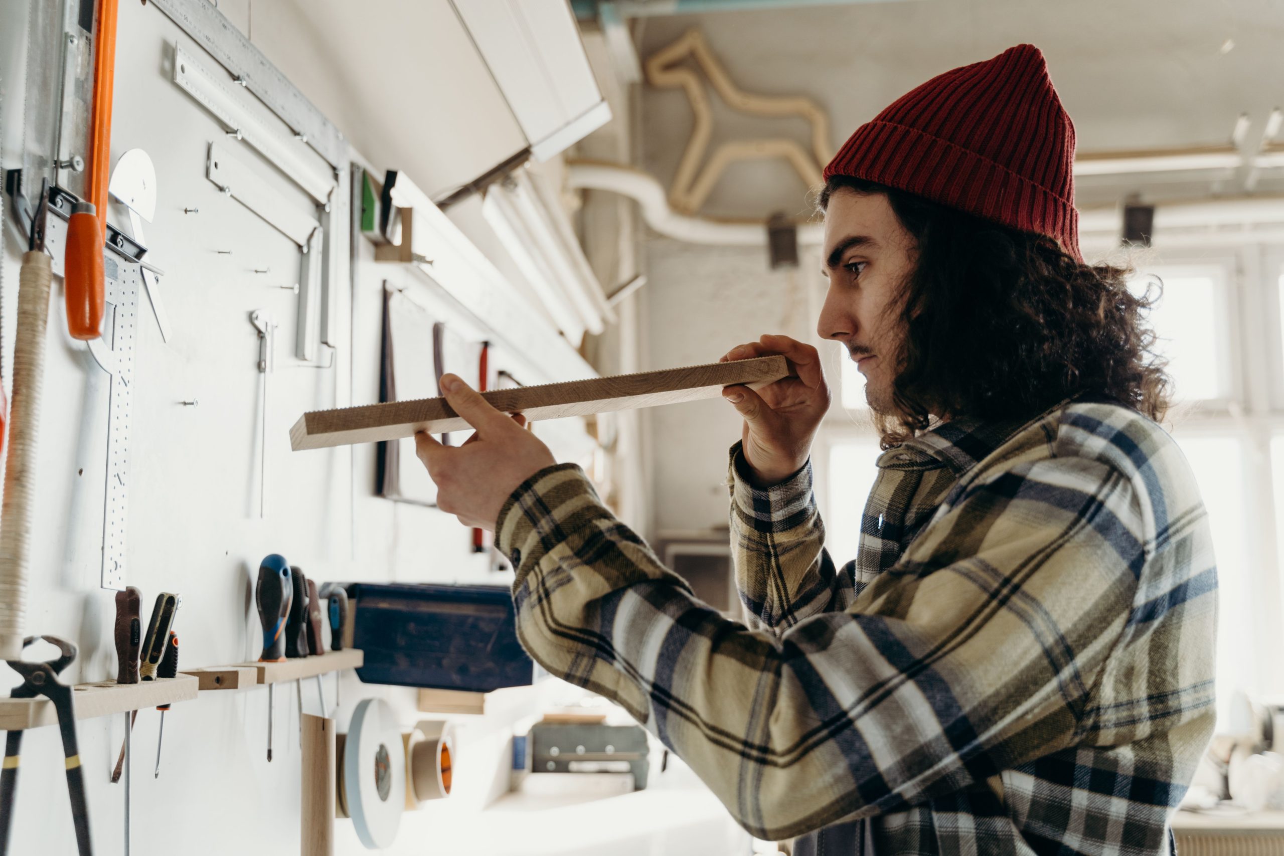 Jeune apprenti menuisier mesurant une planche de bois